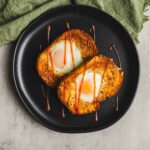 Fried egg in bread, topped with ketchup and served on a black plate, with a green napkin, perfect for breakfast or brunch.