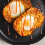 Fried eggs in potato cakes with ketchup drizzle on black plate, delicious breakfast or brunch dish, crispy potato scones with soft eggs, perfect comfort food, hearty and flavorful recipe, easy to assemble.