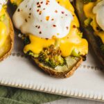 Roasted sweet potato boats topped with cheesy broccoli, sour cream, and chili flakes, served on a white platter.