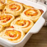 Savory cheesy chicken and vegetable pinwheel casserole baked in a white dish with melted cheese and colorful peppers. Perfect for family dinners or gatherings.