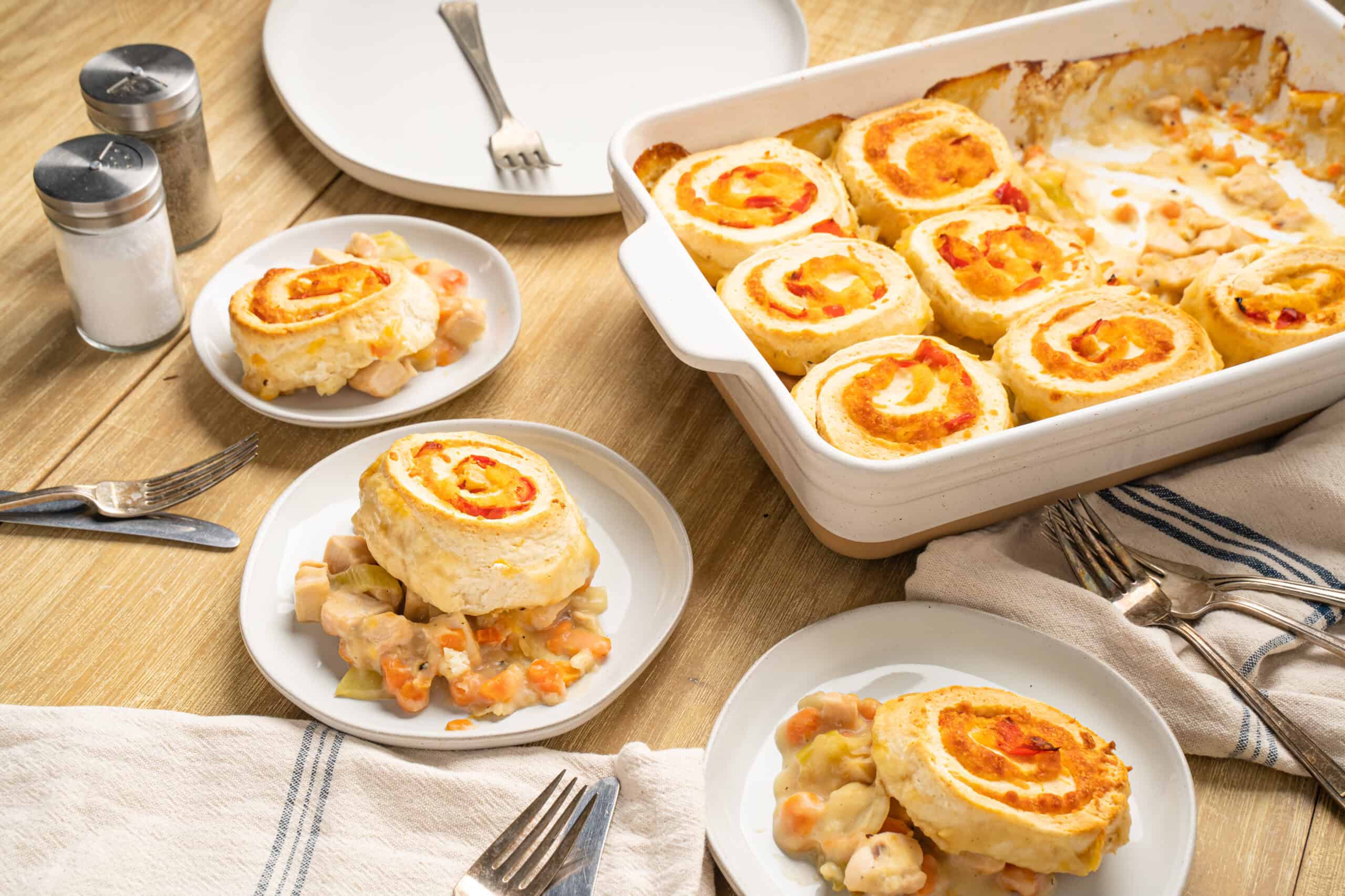 Savory chicken and vegetable stuffed roll-ups served with creamy sauce on a white plate.