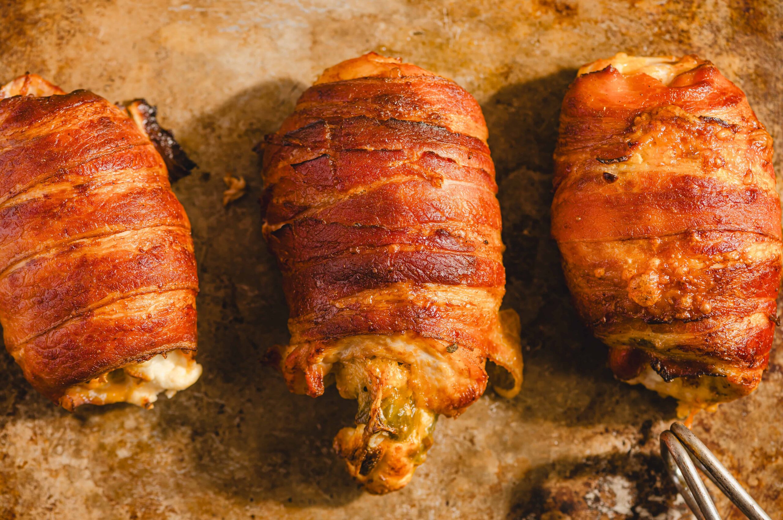 Juicy bacon-wrapped chicken drumsticks on a baking sheet, crispy and flavorful, perfect for delicious dinner recipes.