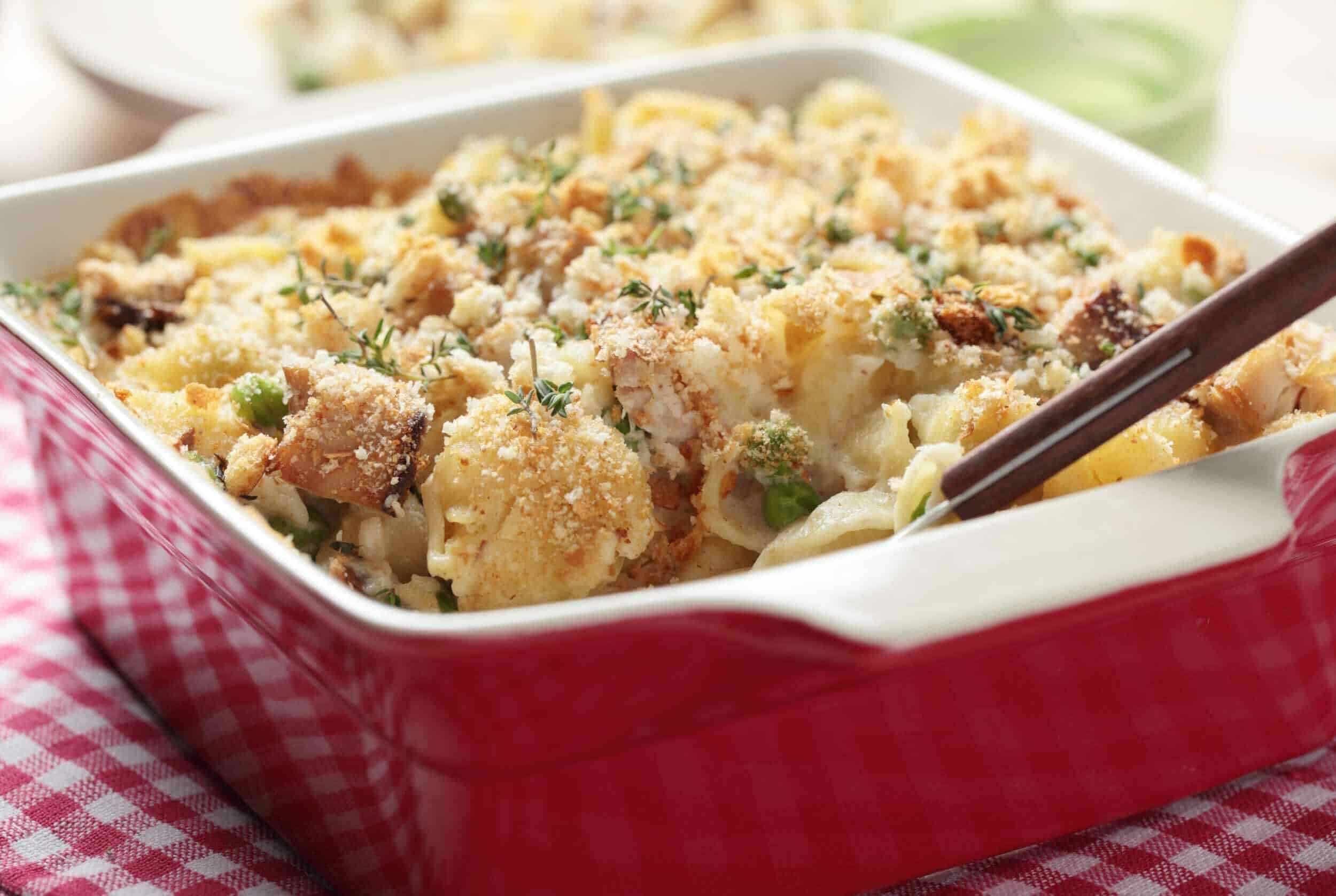 Creamy cauliflower casserole with breadcrumbs, herbs, and melted cheese in a red baking dish. Perfect comfort food for family dinners or holiday gatherings.