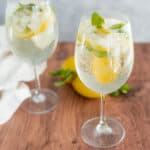 Refreshing lemon mint sparkling water with ice, lemon slices, and fresh mint leaves garnishing chilled glasses on wooden table for a summer drink.