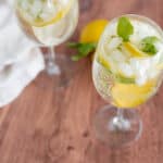 Lemon and mint infused sparkling water with ice in a tall glass, perfect for a refreshing summer drink.