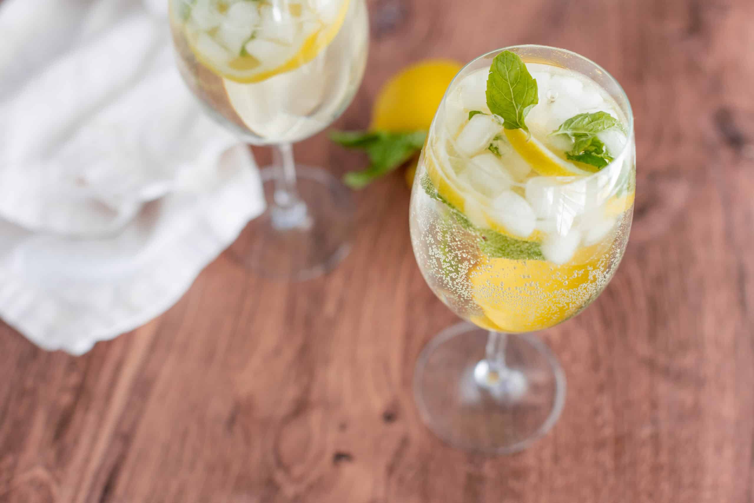 Lemon and mint infused sparkling water with ice in a tall glass, perfect for a refreshing summer drink.
