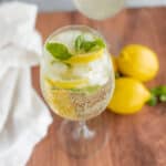 Fresh lemon and mint infused sparkling water with ice in a tall glass, refreshing summer beverage.