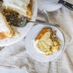 Fluffy vanilla sponge cake with white frosting served on a white plate with a fork.