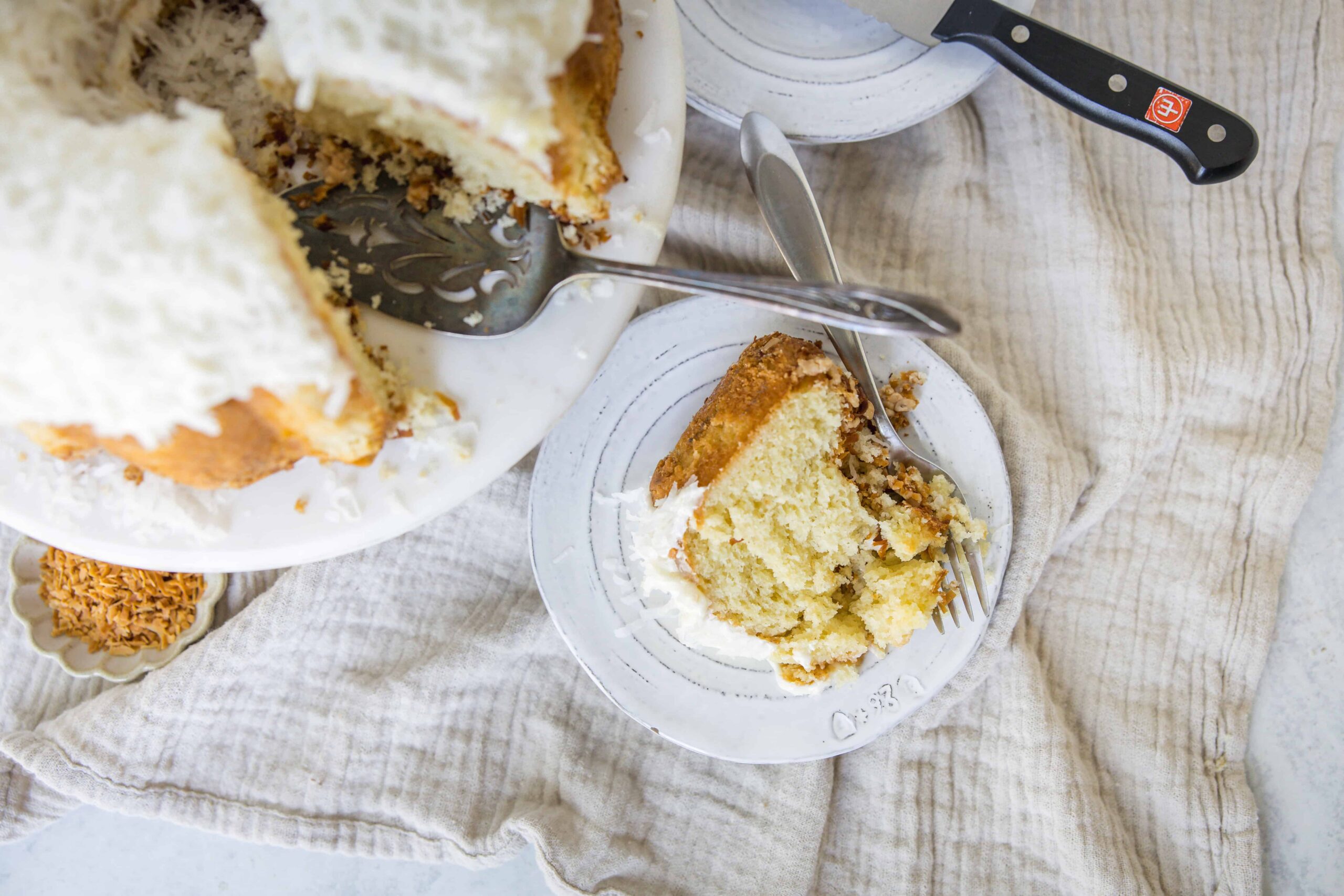 Fluffy vanilla sponge cake with white frosting served on a white plate with a fork.
