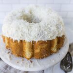 Creamy Coconut Cake with Shredded White Chocolate Topping on White Cake Stand.