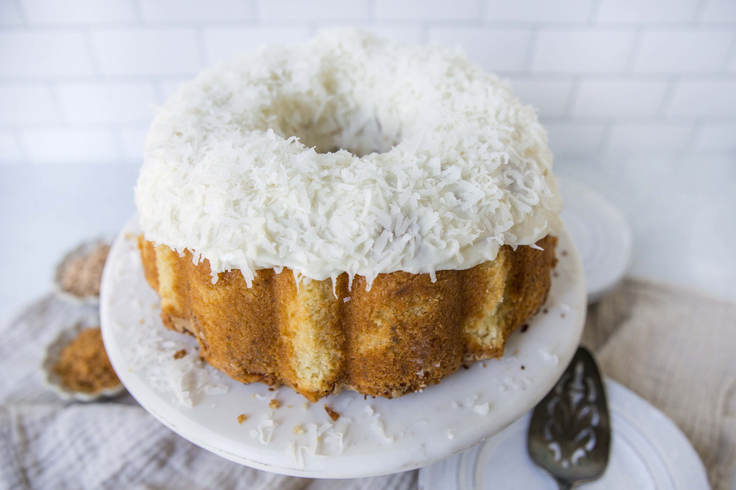 Creamy Coconut Cake with Shredded White Chocolate Topping on White Cake Stand.