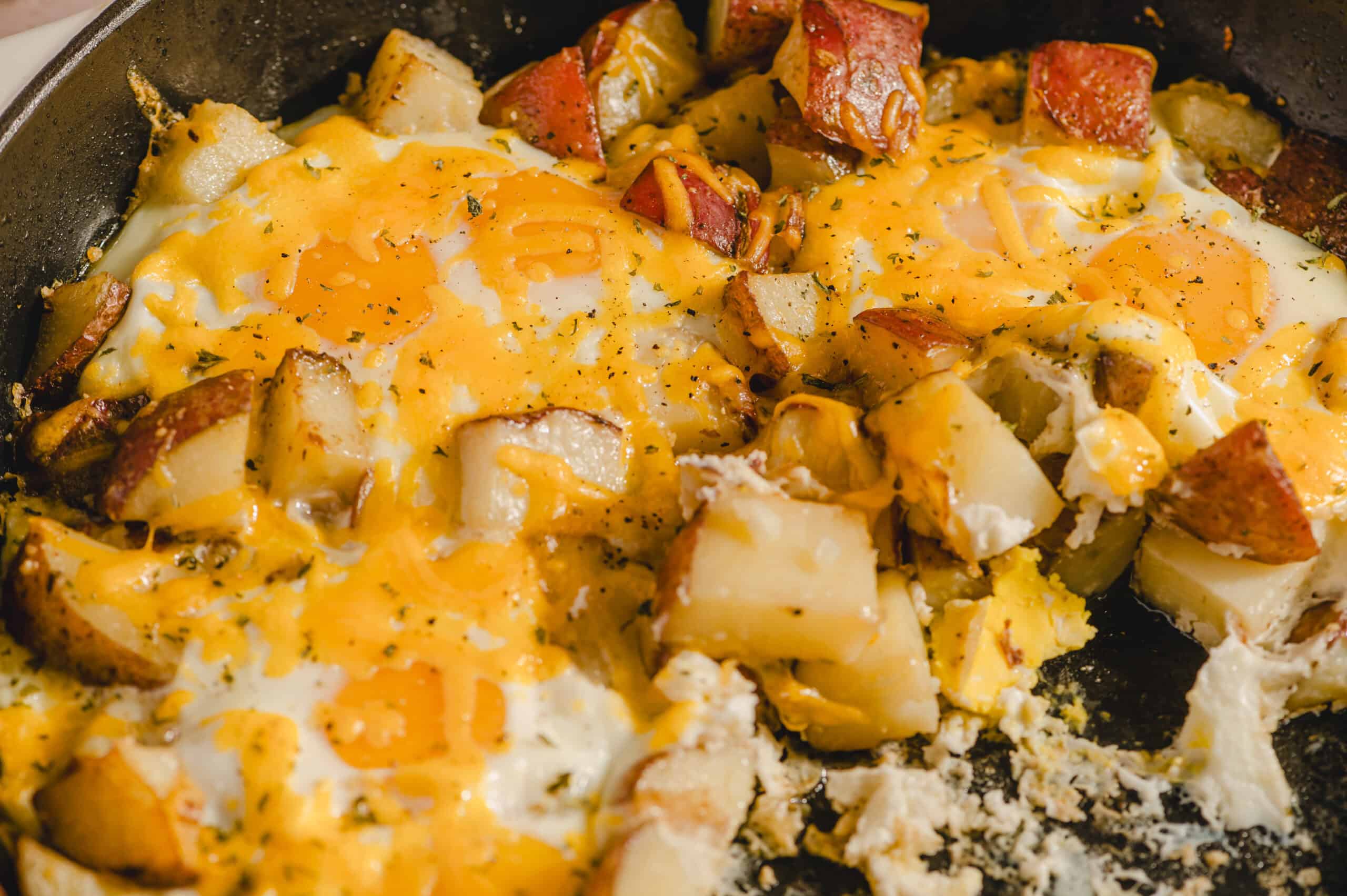 Juicy breakfast skillet with eggs, diced potatoes, ham, and melted cheese close-up. Perfect for breakfast, brunch, or hearty morning meals with savory flavors.