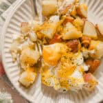 Crispy roasted potatoes with melted cheese and a perfectly cooked sunny side up egg, served on a white plate for breakfast or brunch.