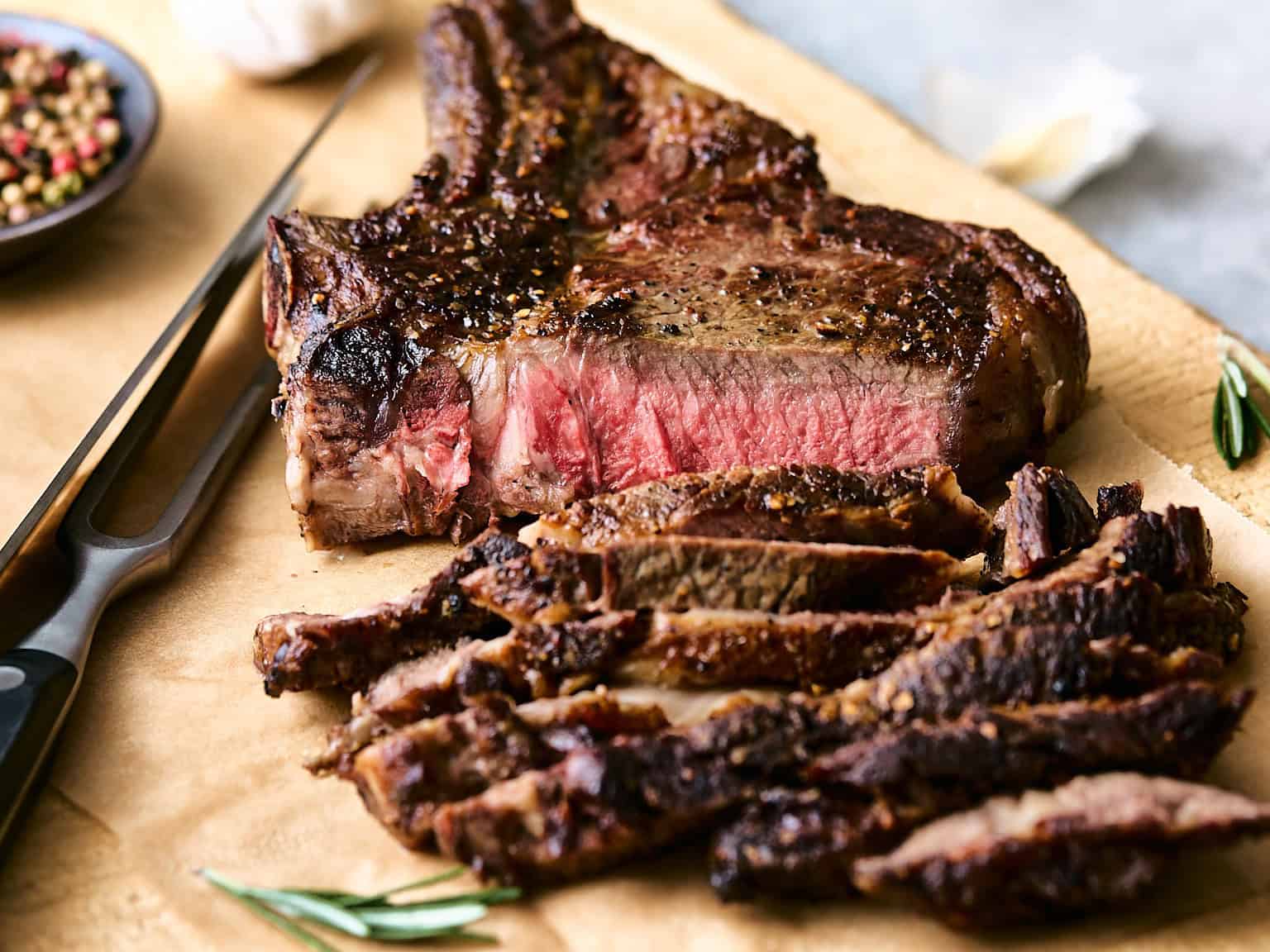 Juicy, perfectly cooked medium-rare steak with a seared crust on a wooden cutting board, sliced to showcase the tender, flavorful interior, ready to serve as a delicious main course.
