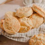 Buttermilk biscuits on a checkered cloth, showcasing golden, flaky crusts and soft interiors, perfect for breakfast or side dishes, emphasizing homemade baking and comfort food.
