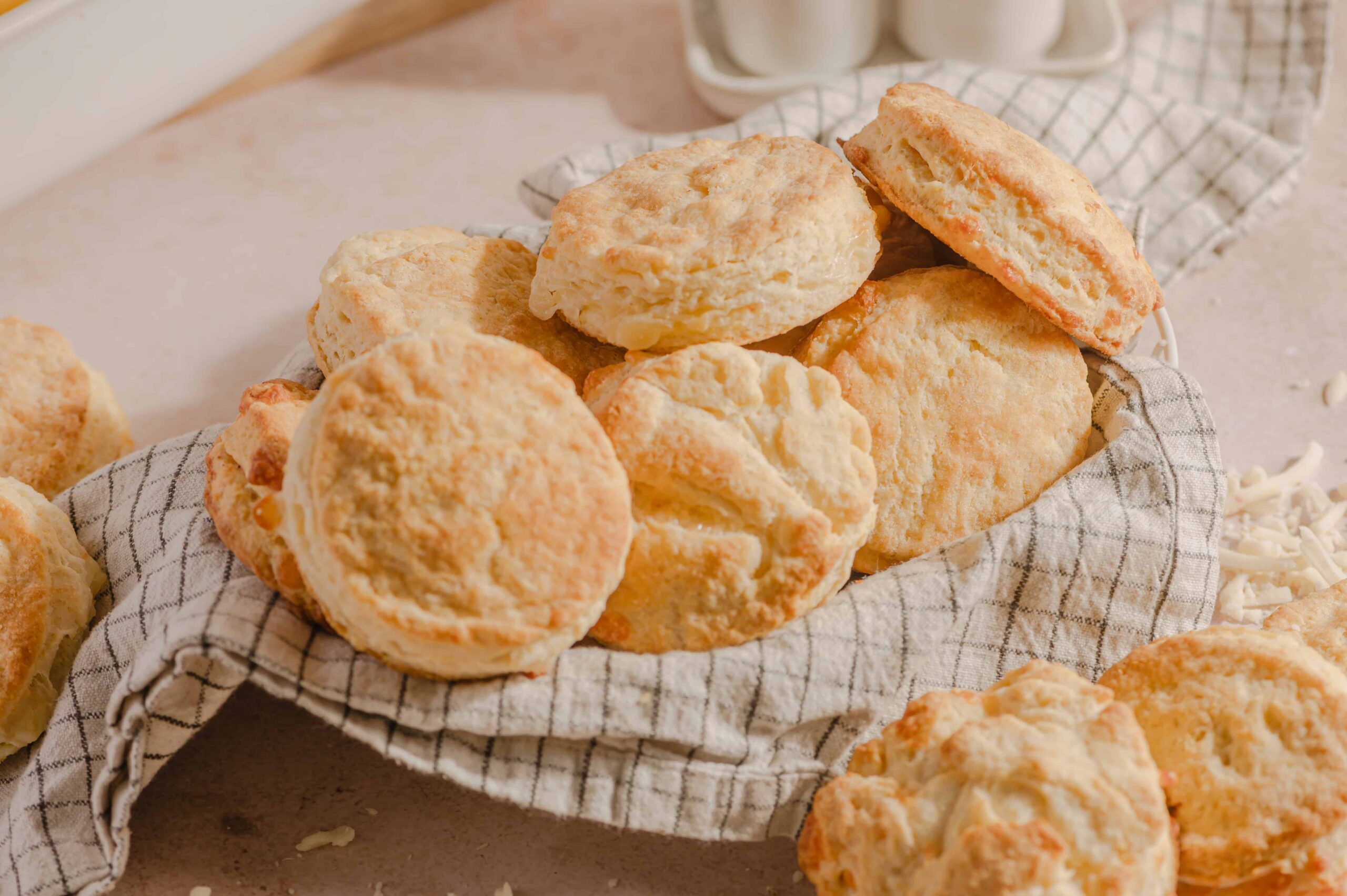 Buttermilk biscuits on a checkered cloth, showcasing golden, flaky crusts and soft interiors, perfect for breakfast or side dishes, emphasizing homemade baking and comfort food.