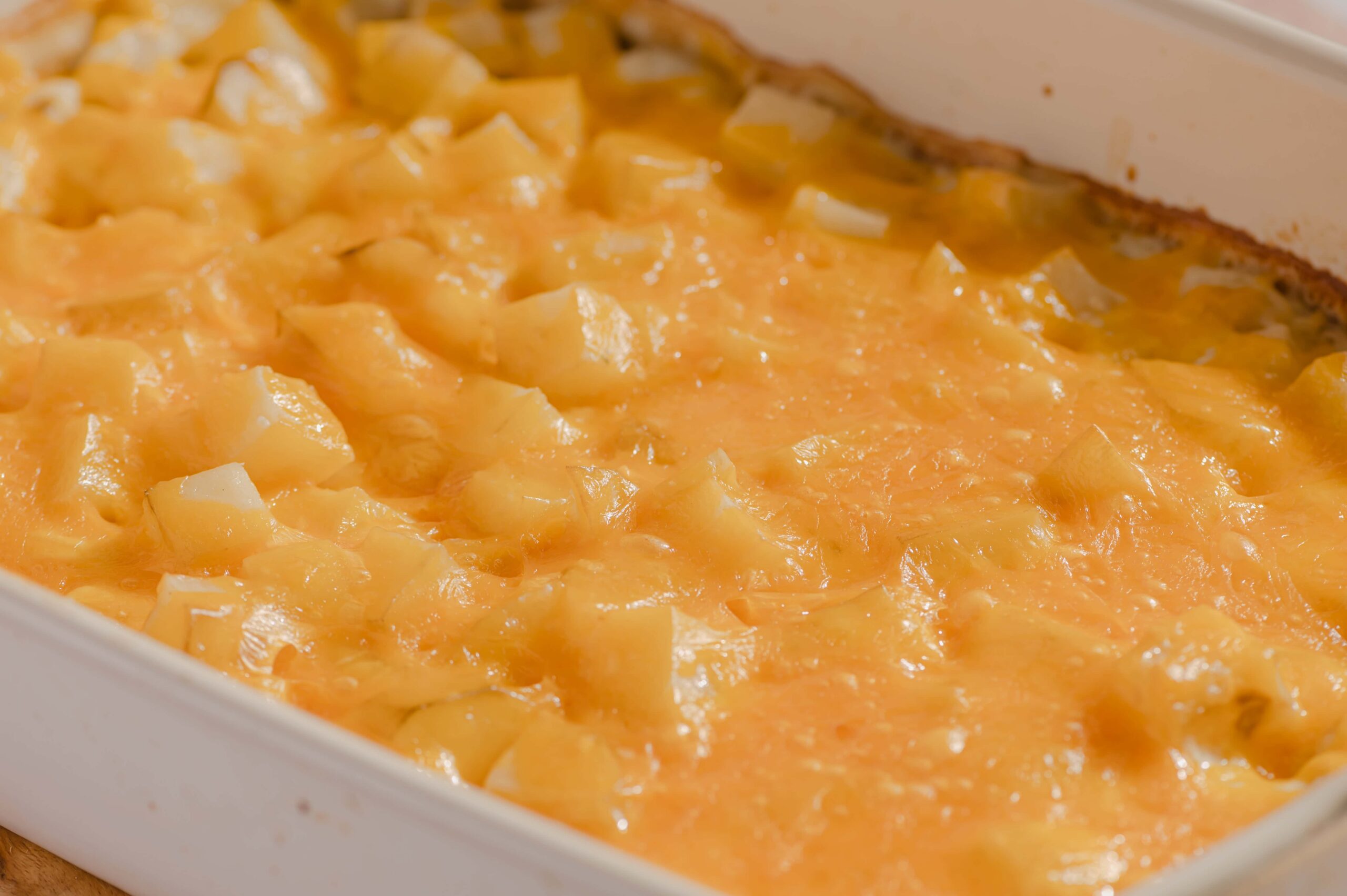 Creamy homemade breakfast casserole with melted cheese and diced potatoes in a white baking dish. Perfect for easy brunch or comfort food meals.