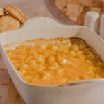 Creamy cheesy potato casserole with melted cheddar cheese and diced potatoes served in a white baking dish. Perfect comfort food for family dinners and gatherings.