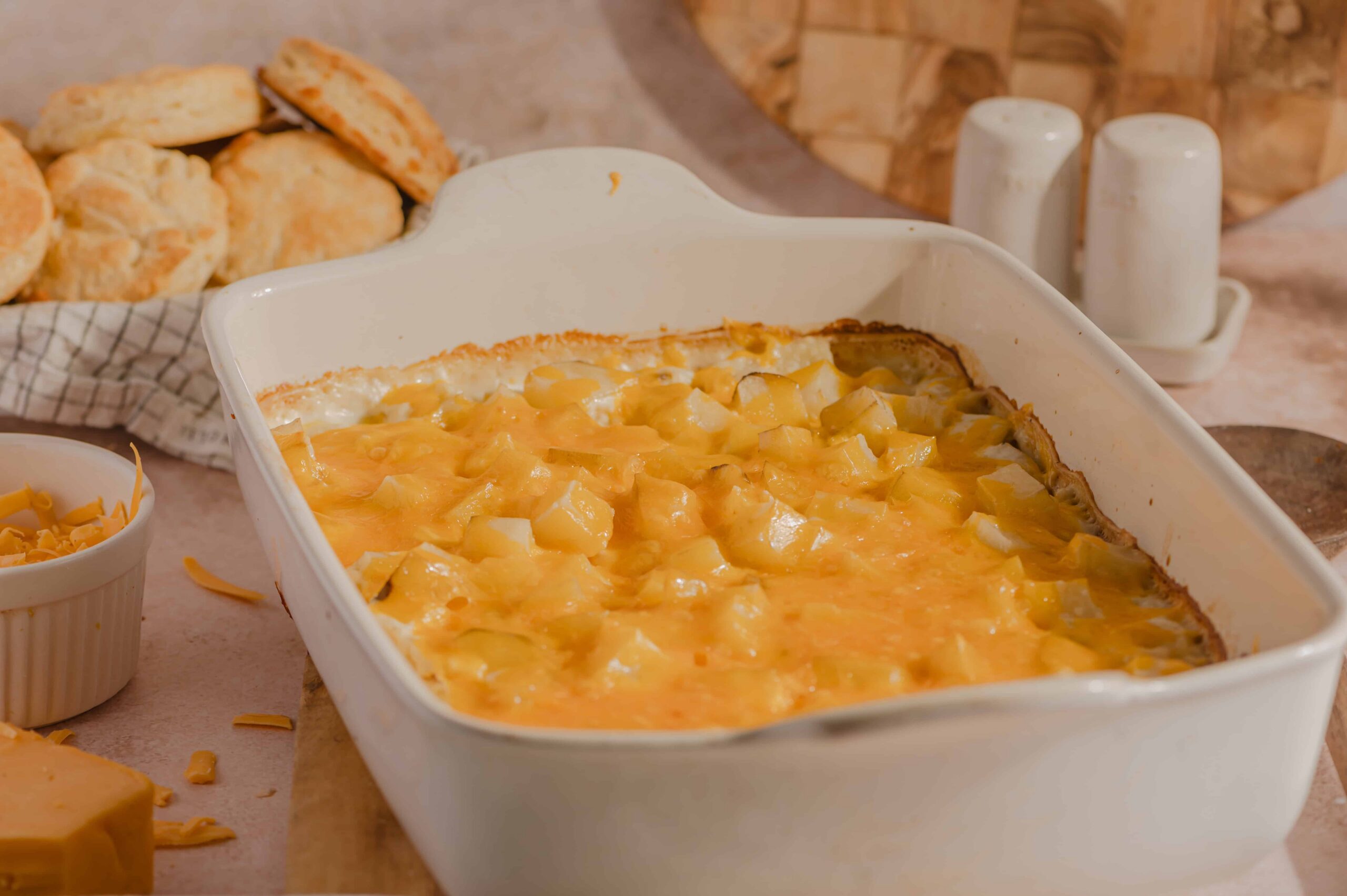 Creamy cheesy potato casserole with melted cheddar cheese and diced potatoes served in a white baking dish. Perfect comfort food for family dinners and gatherings.