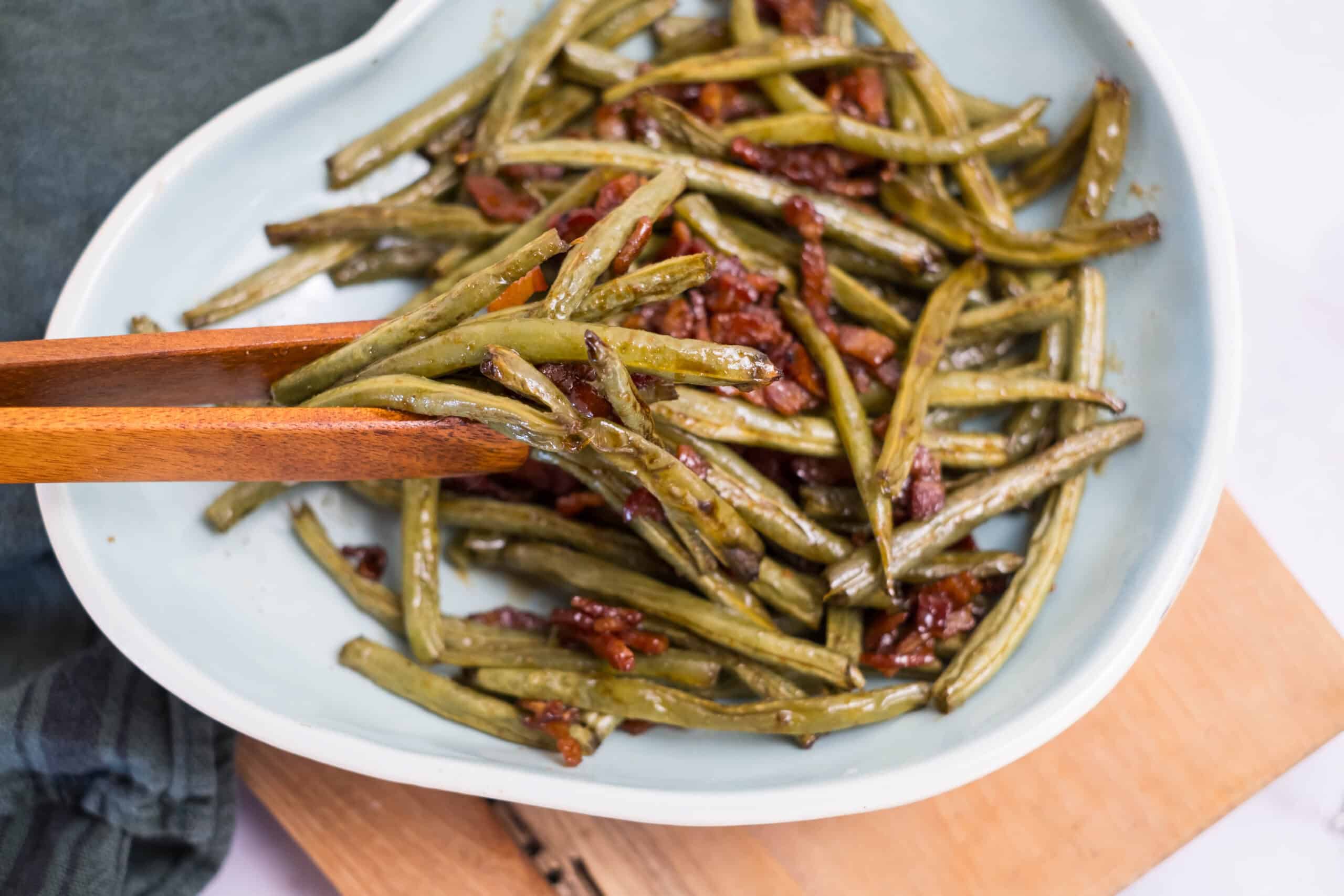 Green beans with bacon, garlic, and herbs in a white dish.