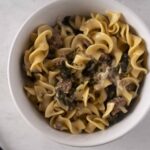 Creamy beef and spinach tortellini in a rich sauce served in a white bowl, perfect for a comforting meal.
