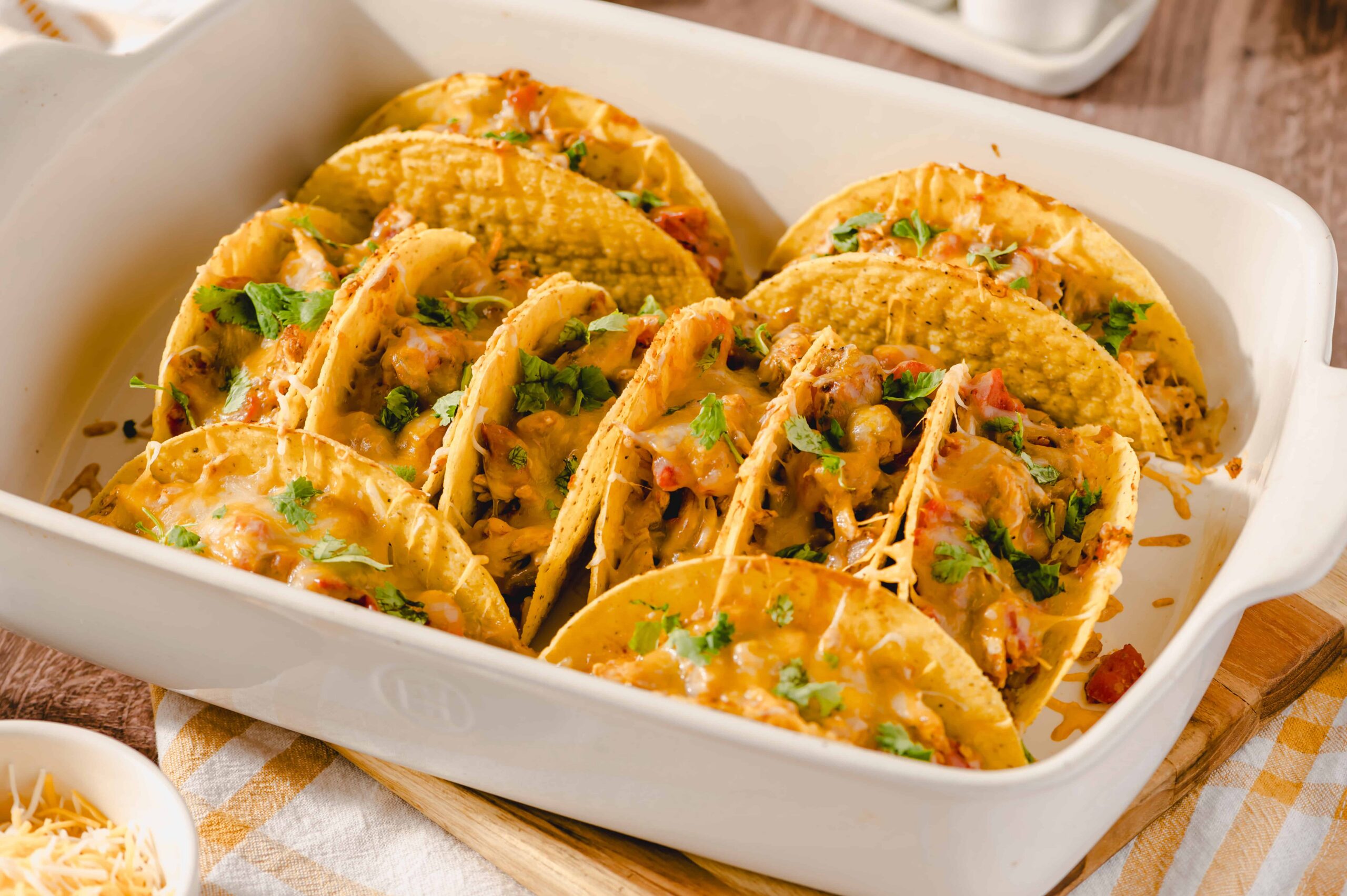 Savory beef and chicken tacos with melted cheese, fresh cilantro, and flavorful toppings in a white serving dish. Perfect for a delicious Mexican meal.