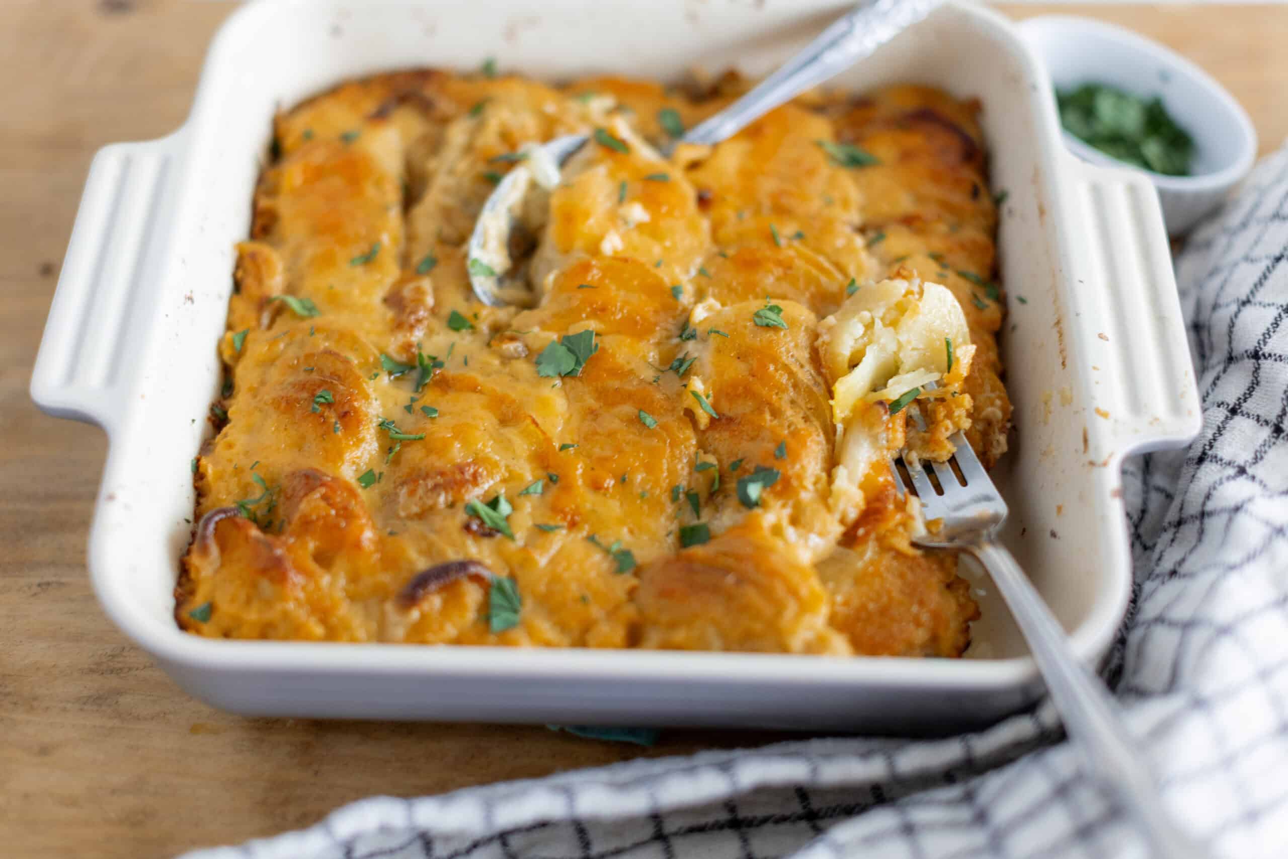 Creamy baked buffalo chicken casserole topped with melted cheese and fresh cilantro, served in a white baking dish with a side of green dip, perfect for comfort food lovers and family dinners.