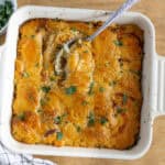 Creamy baked chicken casserole with melted cheese and fresh herbs in a white baking dish. Perfect comfort food for family dinners.