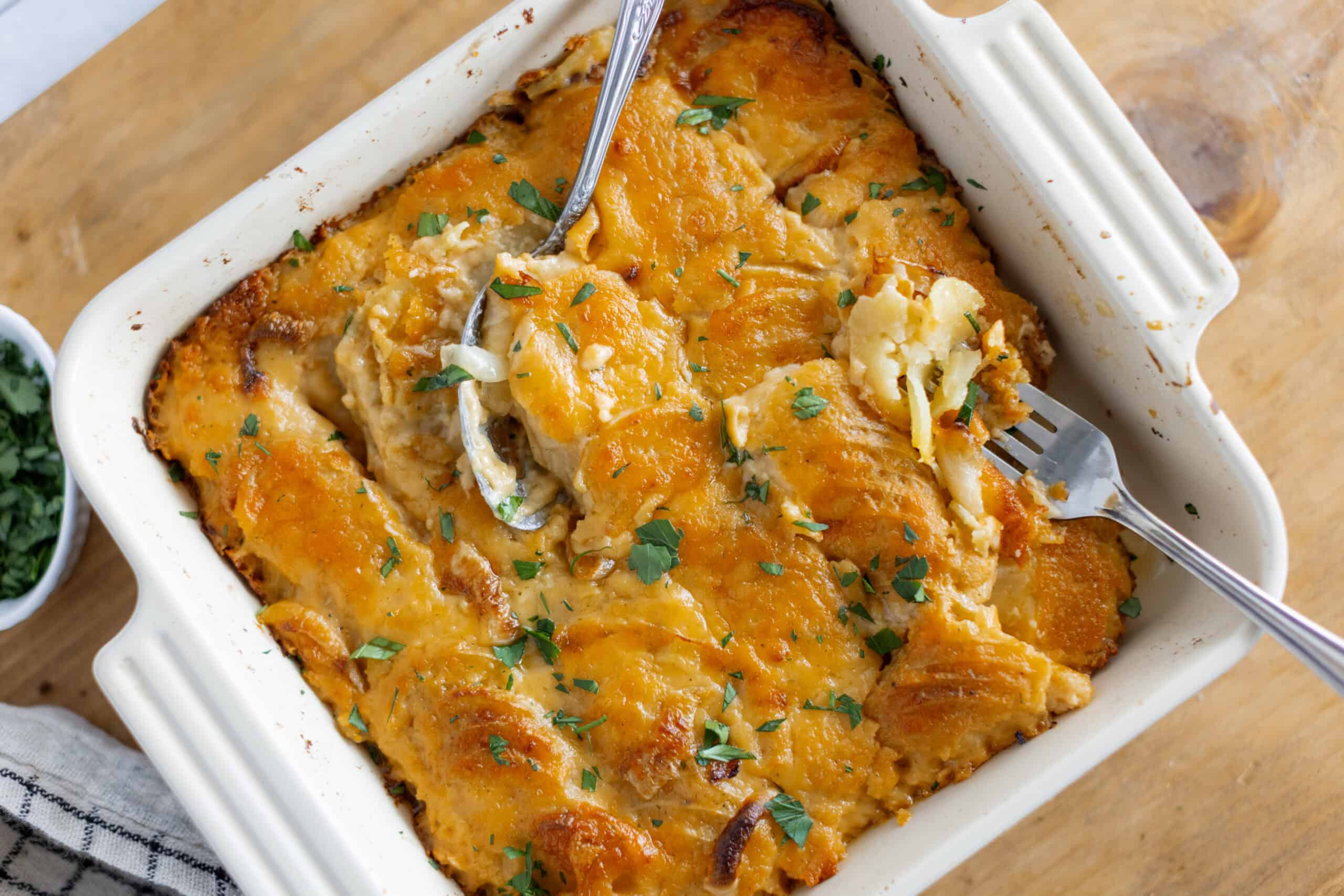 Creamy chicken casserole with melted cheese and herbs in a white baking dish, easy family-friendly dinner recipe.