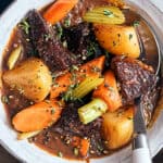 Hearty beef and vegetable stew in a rustic bowl with carrots, potatoes, celery, and tender beef chunks, garnished with fresh herbs and served with crusty bread. Perfect comfort food for cold days.