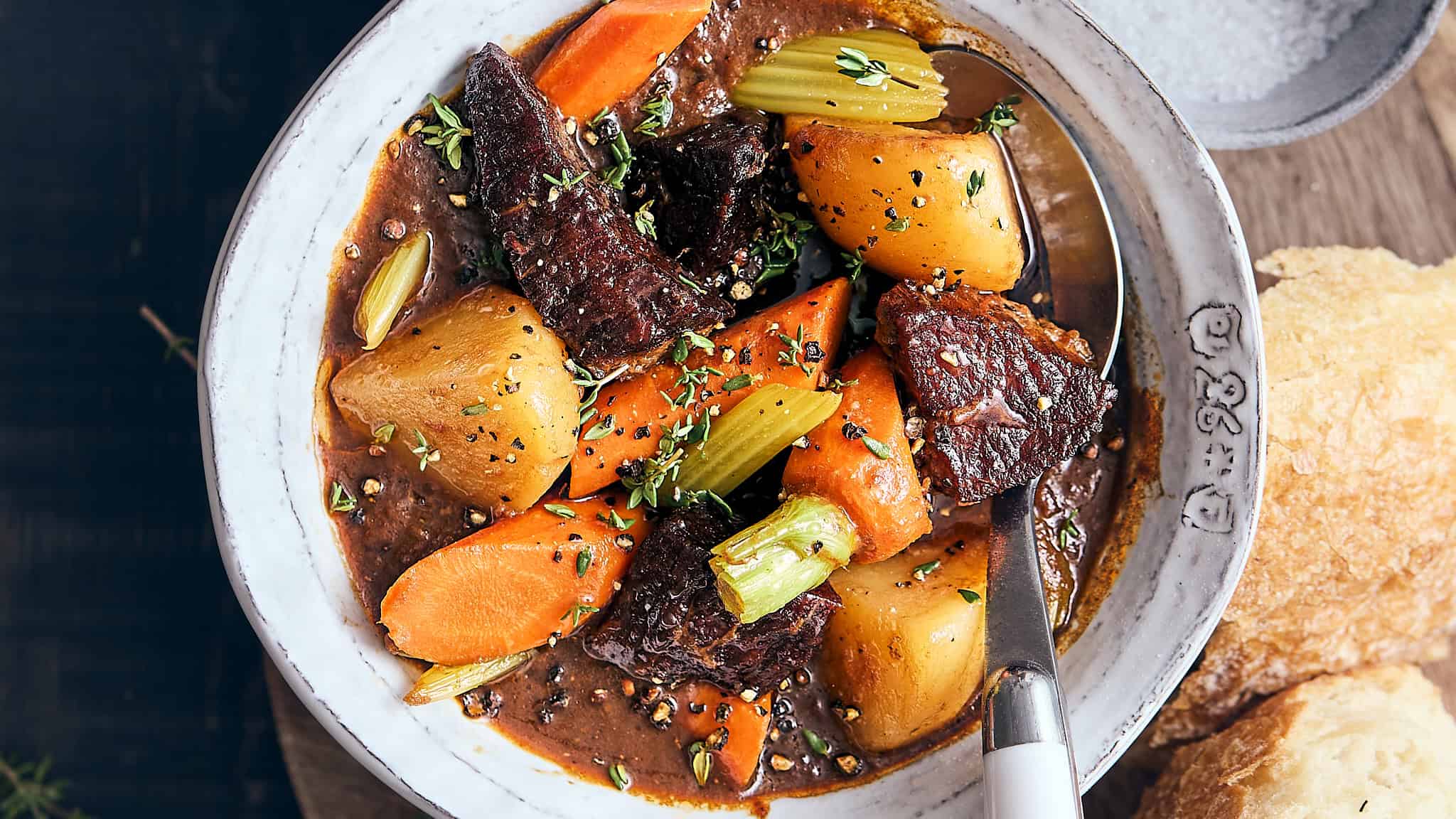 Hearty beef and vegetable stew in a rustic bowl with carrots, potatoes, celery, and tender beef chunks, garnished with fresh herbs and served with crusty bread. Perfect comfort food for cold days.