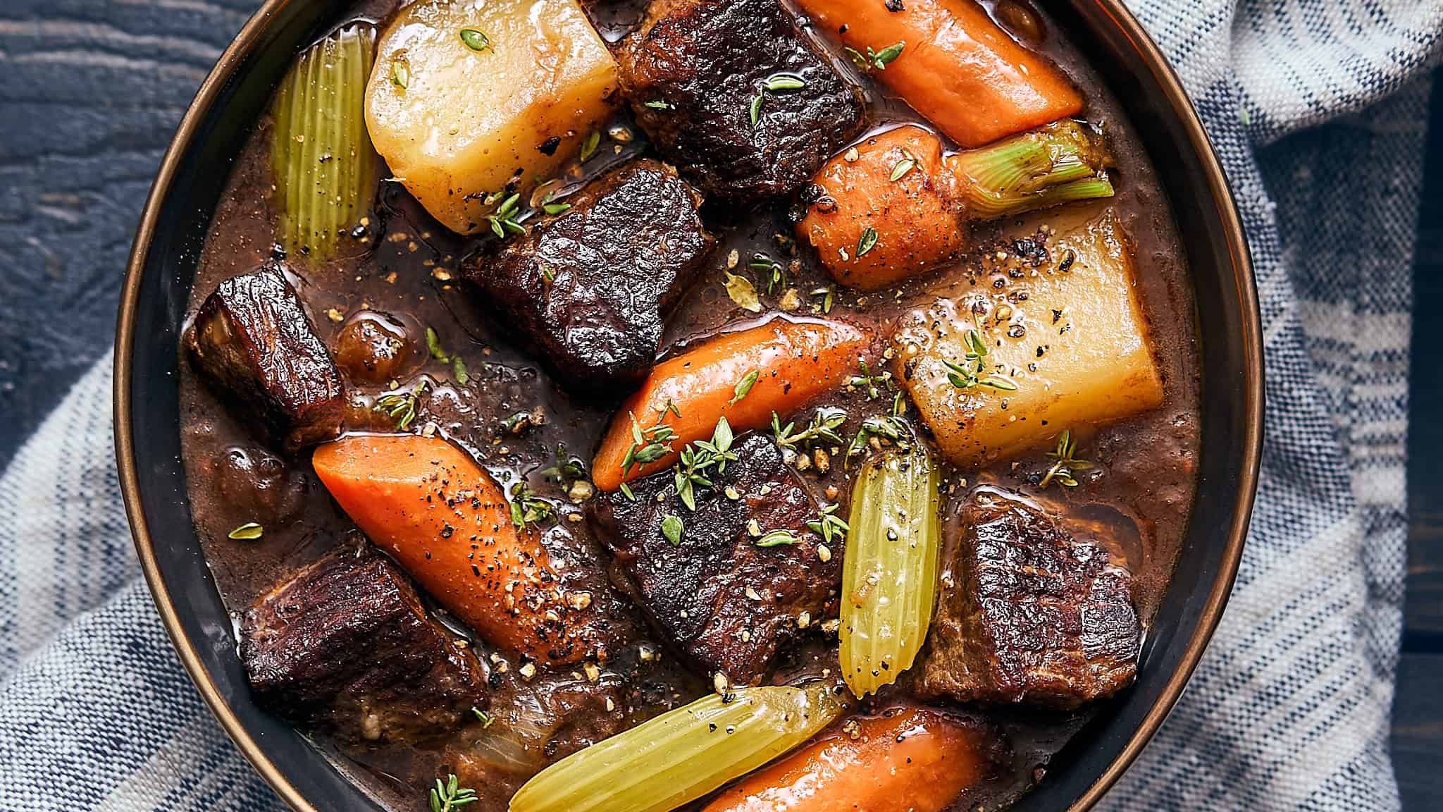 Tender beef stew with carrots, potatoes, celery, and herbs in a savory broth, served in a rustic bowl for hearty comfort food. Perfect for slow-cooked, family-friendly dinners.