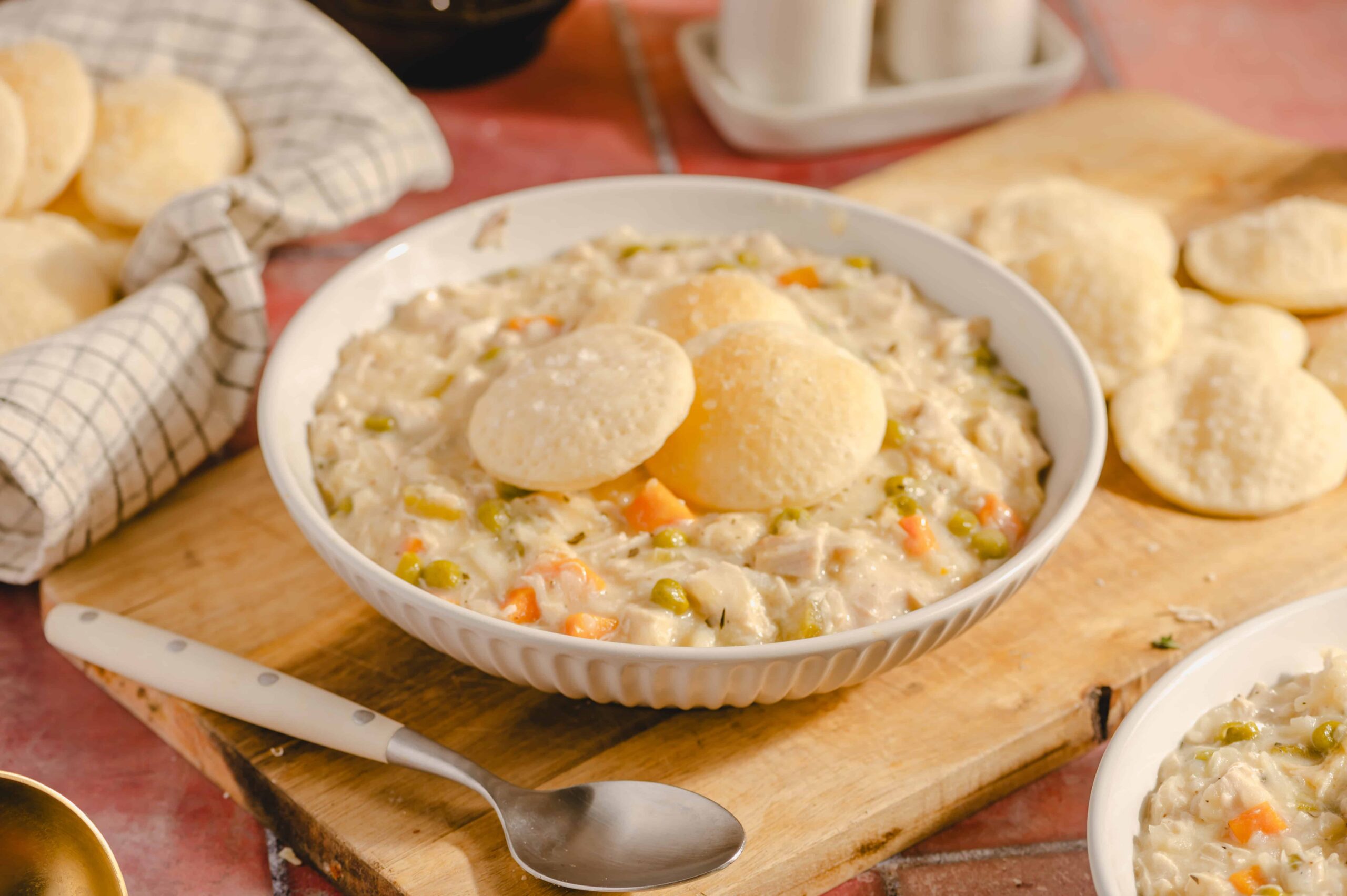 Creamy chicken and vegetable pot pie filling with dumplings served in a white bowl - comfort food recipe.