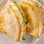 Cheese and chicken burrito wrapped in a flour tortilla, served on a white plate with fresh lettuce inside, perfect for a quick and flavorful meal.