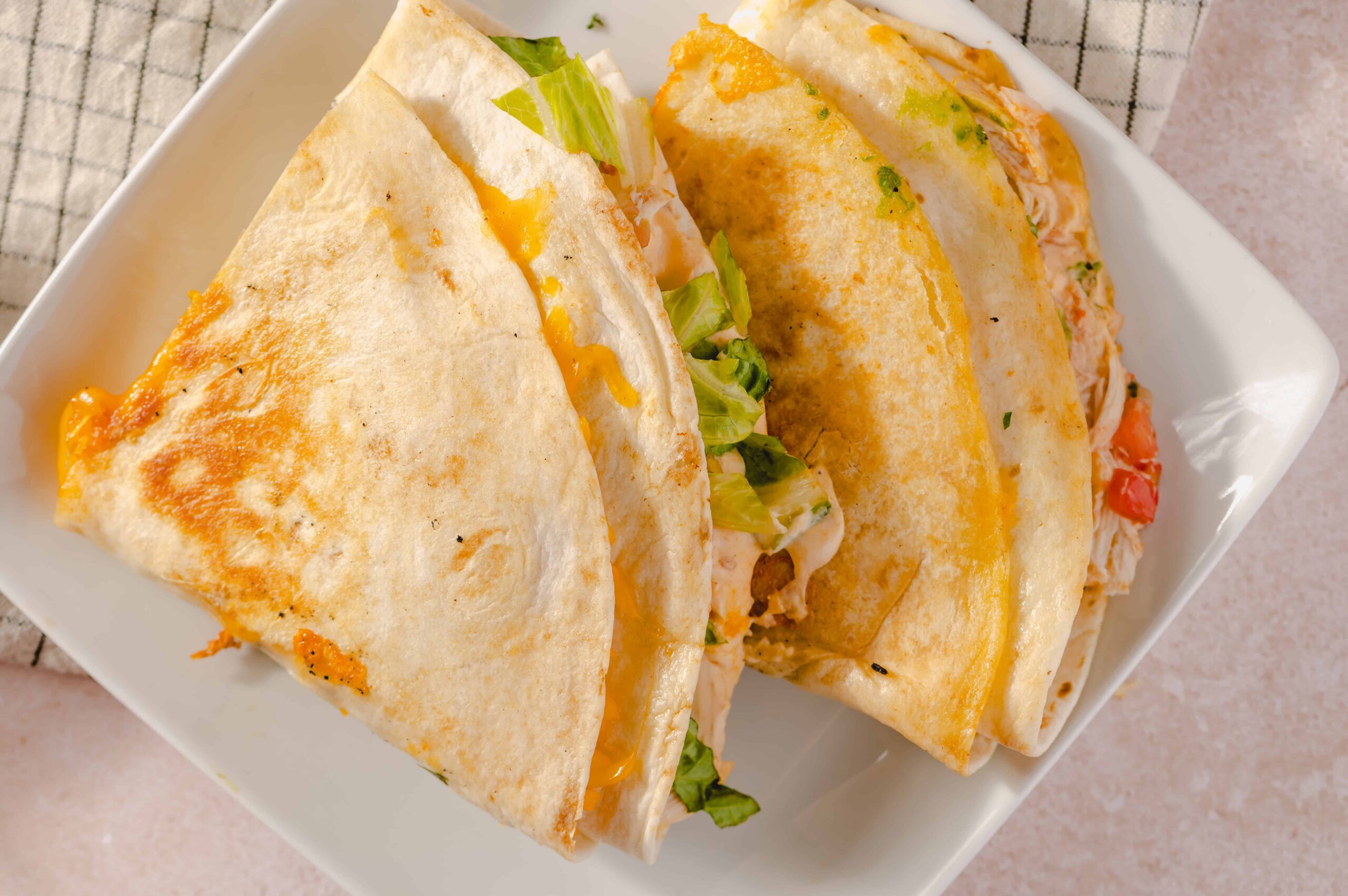 Cheese and chicken burrito wrapped in a flour tortilla, served on a white plate with fresh lettuce inside, perfect for a quick and flavorful meal.