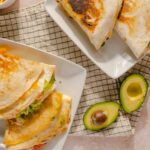 Creamy chicken and avocado quesadillas with melted cheese and fresh ingredients, served with ripe avocado halves for a healthy, delicious meal or snack.