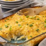 Comforting baked cheesy potato casserole topped with green onions, served in a glass baking dish. Perfect for family dinners or holiday sides.
