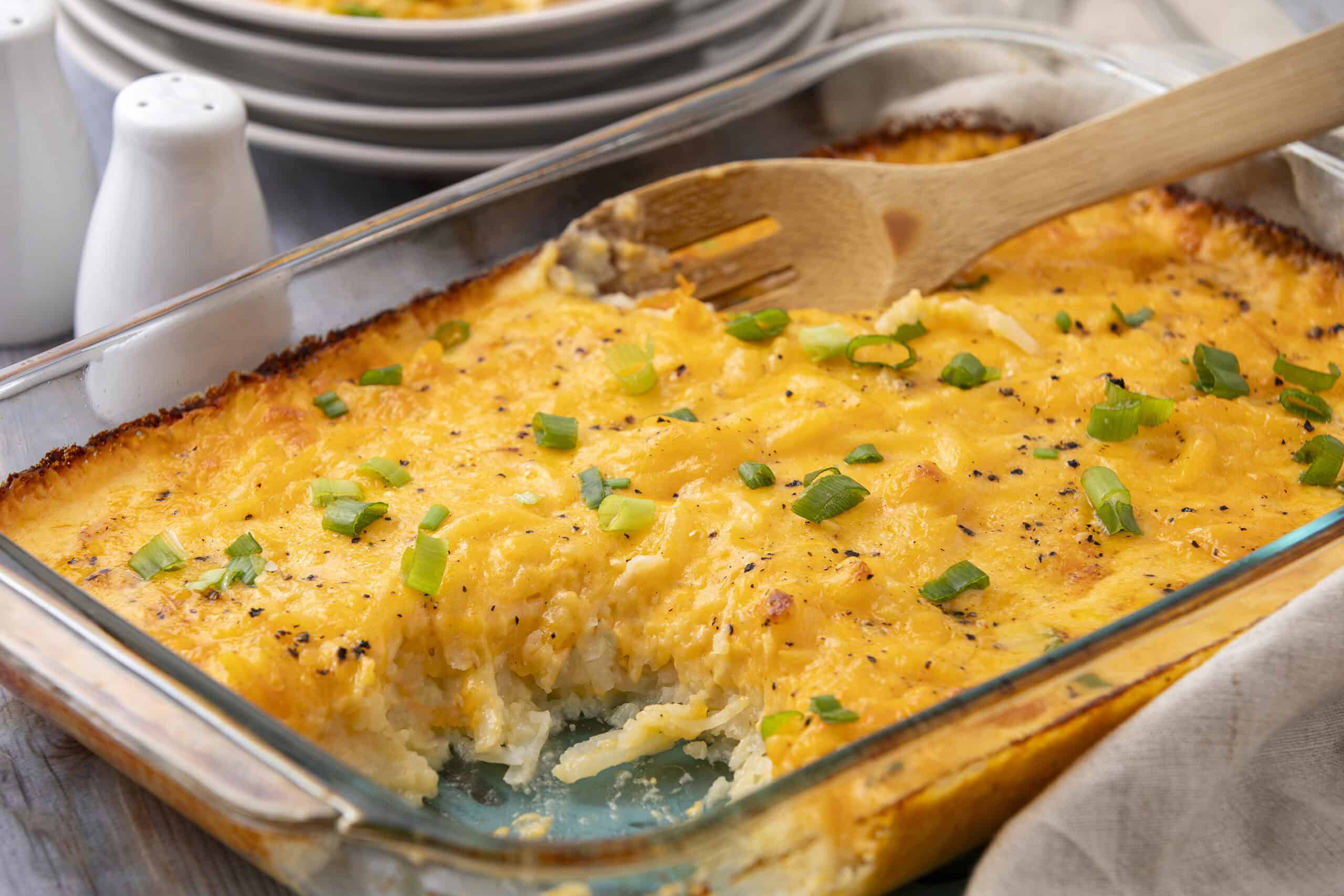 Comforting baked cheesy potato casserole topped with green onions, served in a glass baking dish. Perfect for family dinners or holiday sides.