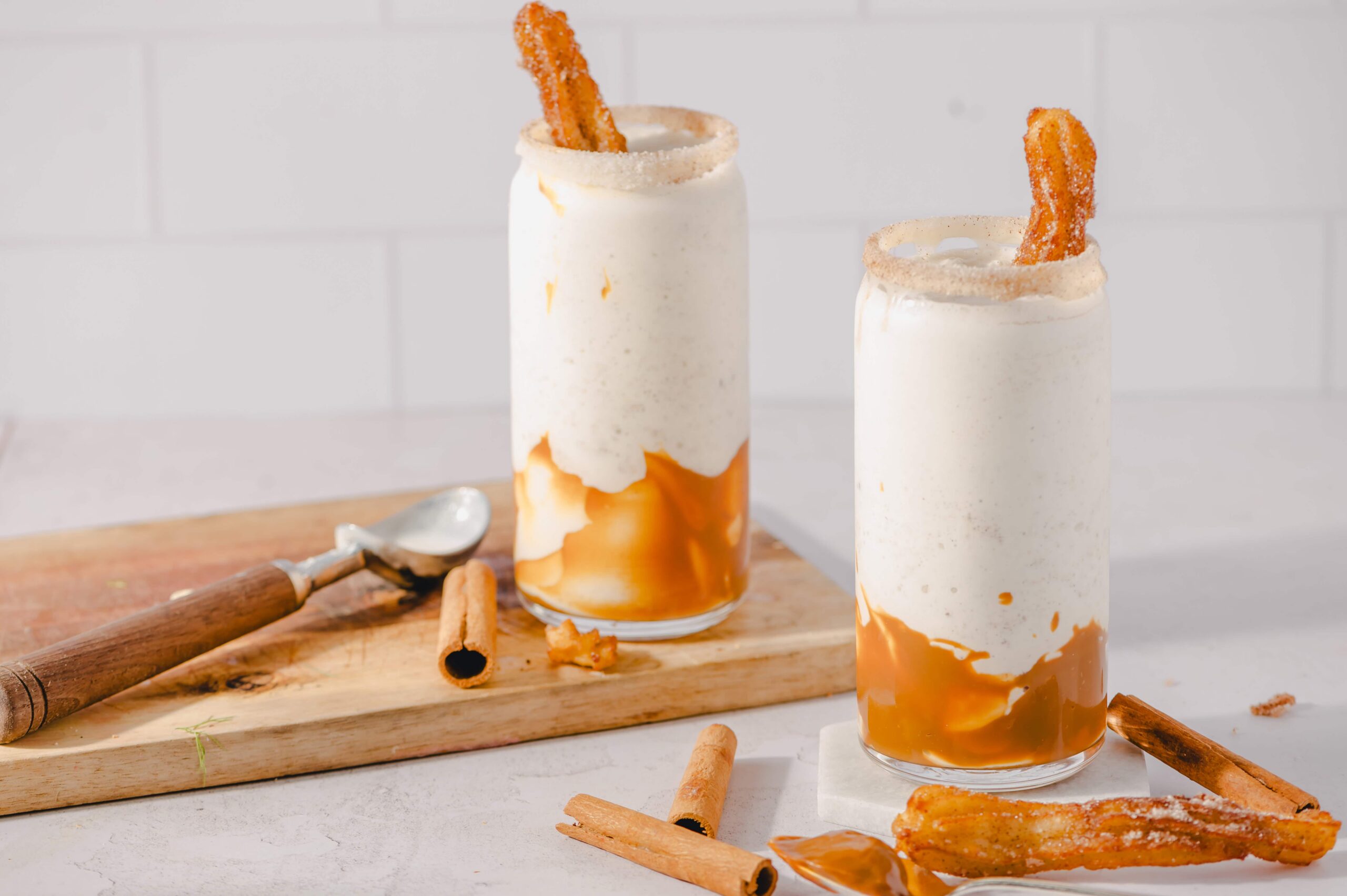 Creamy caramel and cinnamon churro milkshake topped with churros and caramel drizzle for a delicious dessert drink. Perfect for satisfying sweet tooth cravings.