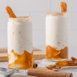 Creamy caramel milkshakes topped with cinnamon sugar churro sticks, served in tall glasses for a delicious dessert or sweet treat.