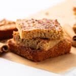 Soft and moist cinnamon coffee cake bars with a crunchy cinnamon sugar topping, perfect for breakfast or snack, served alongside cinnamon sticks on parchment paper.