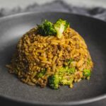 Spaghetti squash with ground beef and broccoli, healthy low-carb meal on black plate, savory vegetable and meat dish, nutritious vegan-friendly recipe, quick dinner idea.