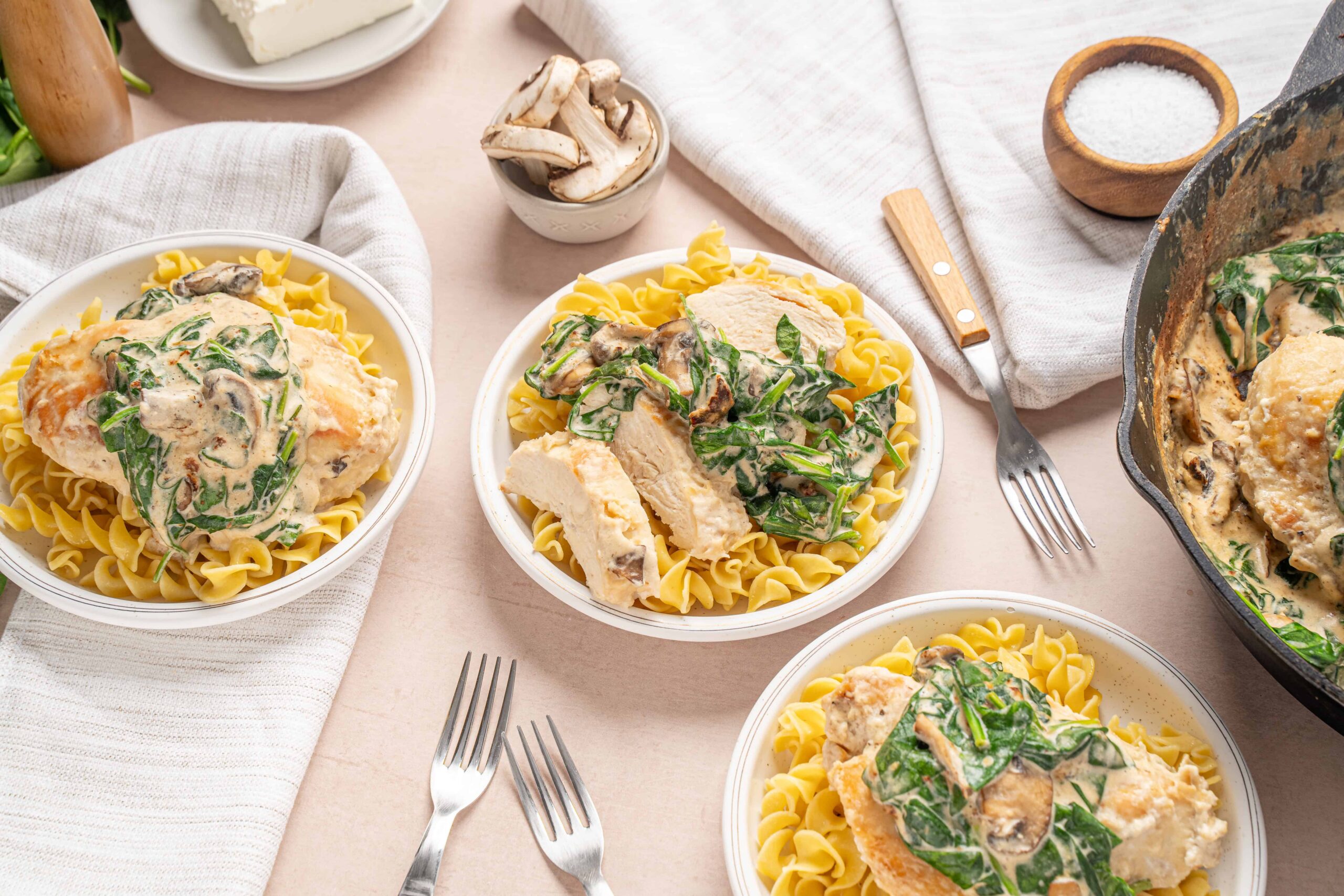 Creamy mushroom and spinach chicken served over pasta in bowl for easy weeknight dinner.