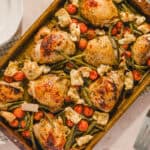 Roast chicken with cherry tomatoes, roasted potatoes, and green beans in a baking dish, a healthy and flavorful meal perfect for dinner or family gatherings.
