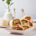 Delicious veggie and meat rolled wraps with fresh lettuce, cucumbers, and peppers, served on a white plate for a healthy snack or light meal.