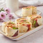 Freshly made wrap sandwiches filled with colorful vegetables and meats, served on a decorative plate for a healthy lunch option.