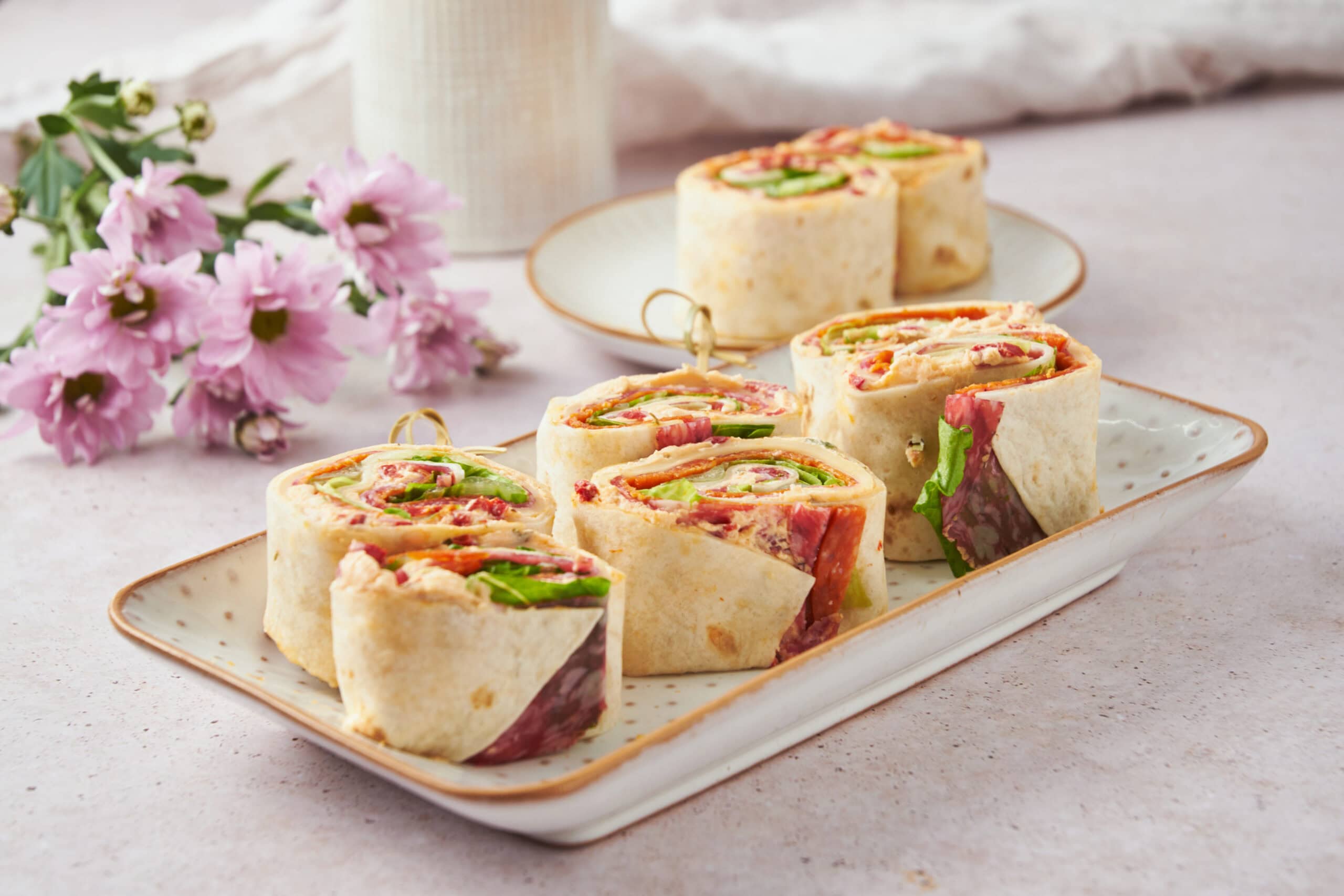 Freshly made wrap sandwiches filled with colorful vegetables and meats, served on a decorative plate for a healthy lunch option.