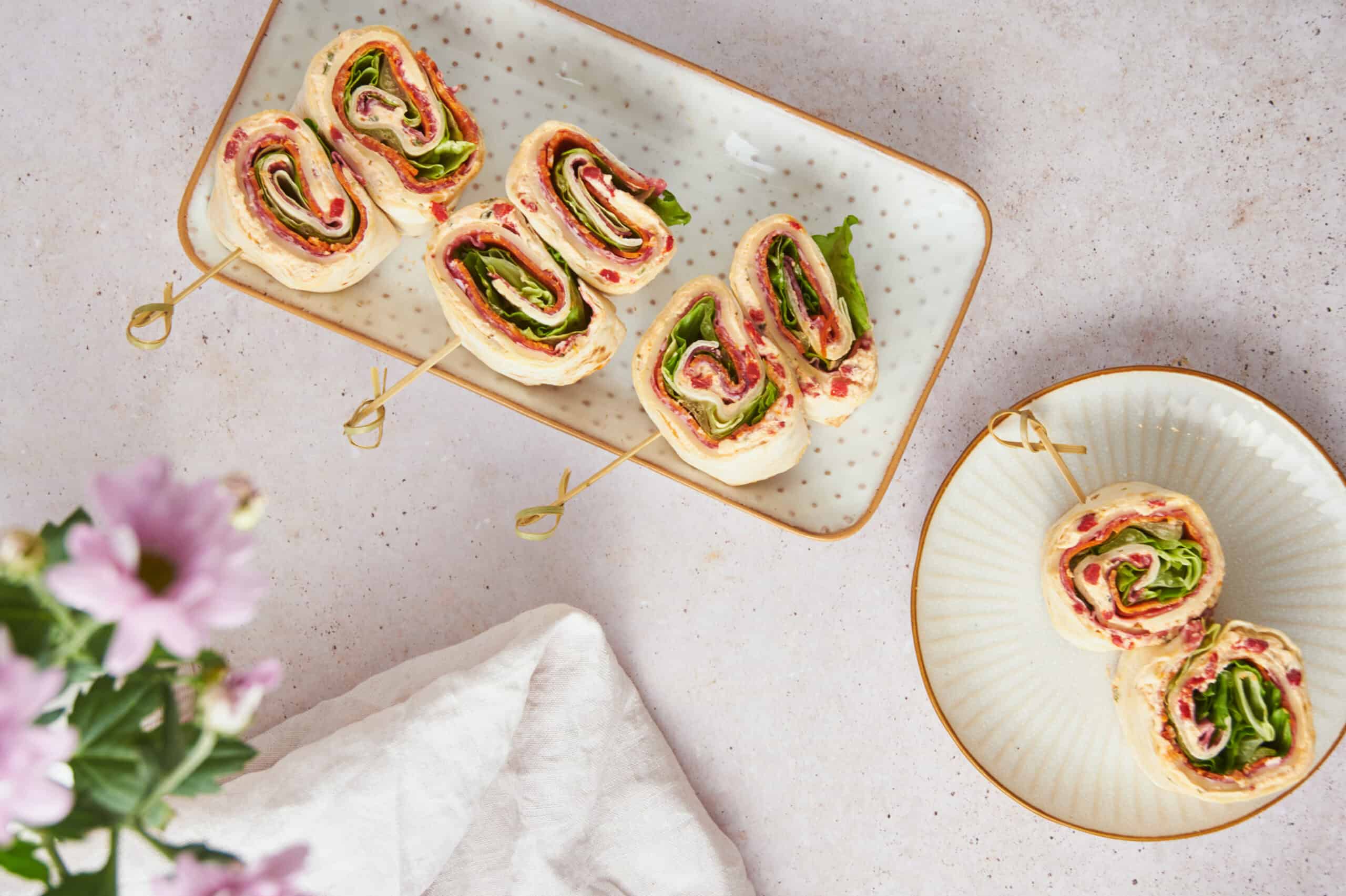 Fresh veggie and cheese wraps on skewers served on decorative plates, healthy and colorful meal ideas, perfect for snacks or appetizers.