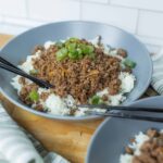 Savory ground beef and rice bowl with green onions in a modern gray bowl, Asian-inspired dish, quick and tasty home-cooked meal.