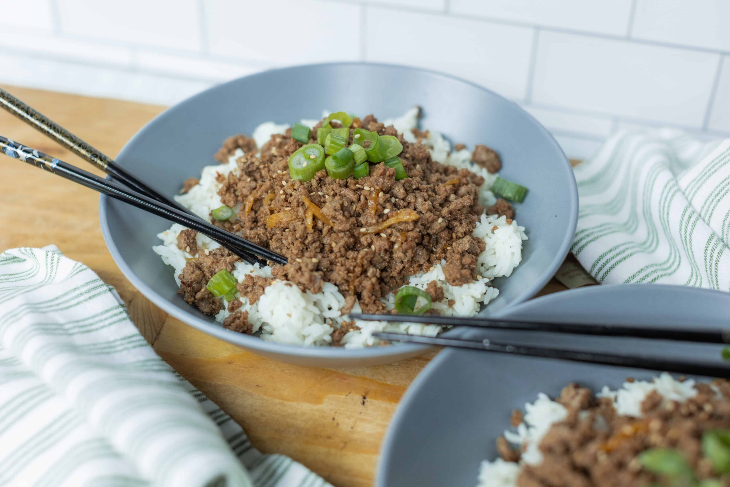 Savory ground beef and rice bowl with green onions in a modern gray bowl, Asian-inspired dish, quick and tasty home-cooked meal.